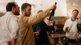 Sommeliers picking up wine bottles and glasses from a table at a Star Wine List of the Year event in London, UK.