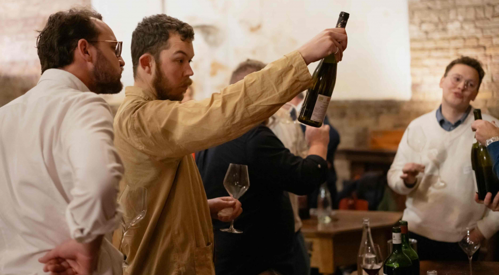Sommeliers picking up wine bottles and glasses from a table at a Star Wine List of the Year event in London, UK.
